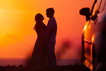 Sunset background of silhouette couple, they travel by carの写真素材