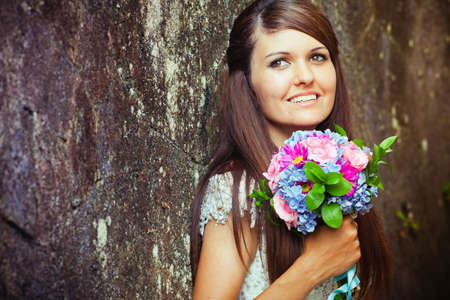 Bride with wedding bouquet at wall backgroundの写真素材