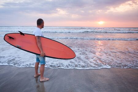 Surfer walking on coast in Bali, Indonesiaの写真素材