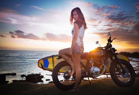 Woman on motorcycle with surfboard at Baliの写真素材