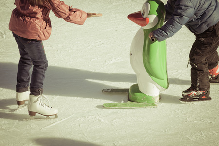 Adorable little girl in winter clothes and hat skating on ice rink at Canadaの写真素材