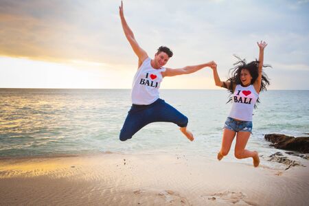 happy couple jumping at the beach with inscriptions of I Love Baliの写真素材