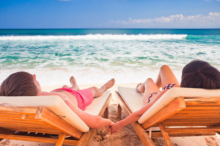 husband with his wife resting near blue ocean, couple just married on beachの写真素材