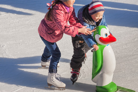 Adorable little girl in winter clothes and hat skating on ice rink at Canadaの写真素材