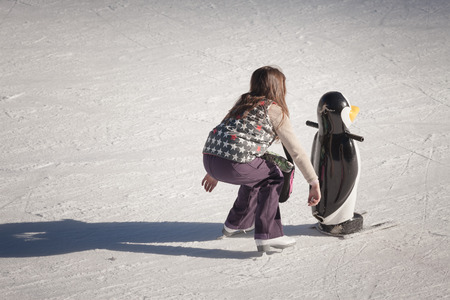 Adorable little girl in winter clothes and hat skating on ice rink at Canadaの写真素材