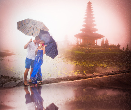 Couple travelling to Asia with umbrellas in bad weatherの写真素材