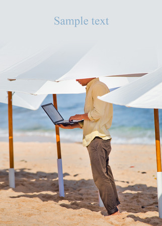 young man working remotely under the umbrella. His work is protectedの写真素材