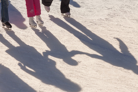 shadow background of family on the ice rink, they hold child's by handsの写真素材