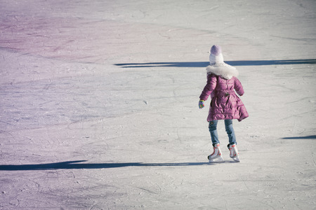 Adorable little girl in winter clothes on ice rink at Canadaの写真素材