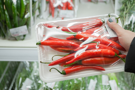 Image of packaged chili peppers with woman hand in the supermarketの写真素材