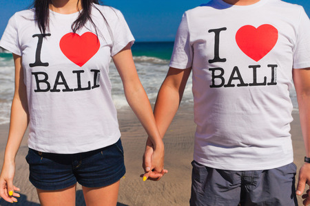 couple holding hands, on their T-shirts written - I love Baliの写真素材