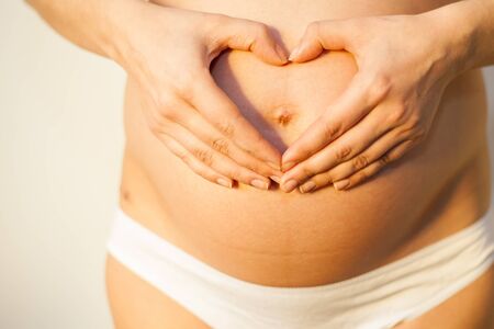 Pregnant woman holding her hands on her stomach in the form of heartの写真素材