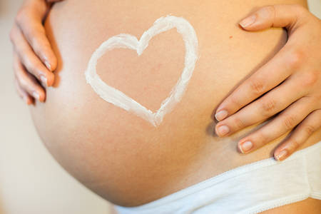Pregnant woman with concept of love, heart applied as a stretch mark creamの写真素材