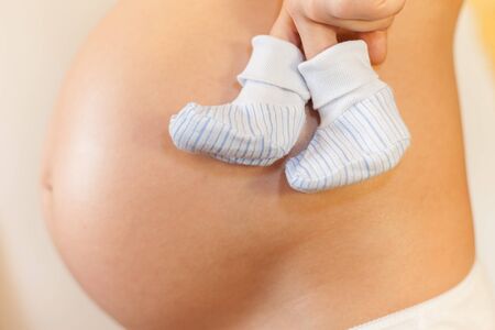 Pregnant woman with concept of walking baby shoesの写真素材