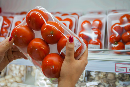 Image of packaged tomato with woman hand in the supermarketの写真素材