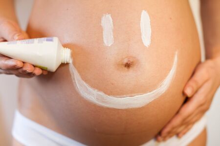Pregnant woman with a smiley on her stomach from the cream for the skinの写真素材