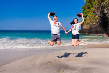 happy couple jumping at the beach with inscription on the shirt - I love Baliの写真素材