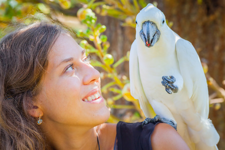 Young woman with white parrot sitting on her shoulder, in  Bali Bird Park, Indonesiaの写真素材