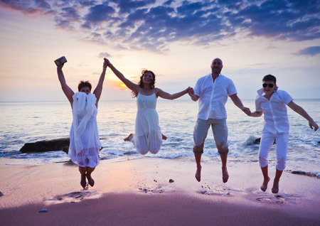 wedding ceremony of mature couple and their family dressed in white at the beachの写真素材