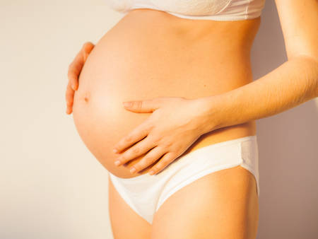 Pregnant woman hugging tummyの写真素材