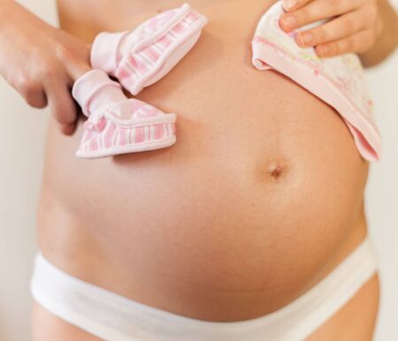 Pregnant woman with baby shoes and hatの写真素材