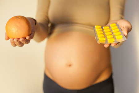 Pregnant woman uses vitamin tablets for healthy nutritionの写真素材