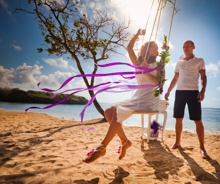 bride ride on a swing near her husbandの写真素材