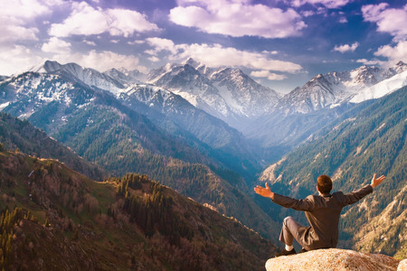 Image of a successful businessman, he sits on the top of mountains on the backgroundの写真素材
