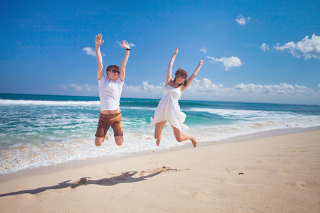 happy couple jumping at the beachの写真素材