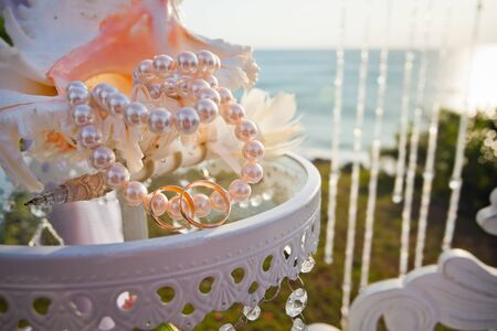 Wedding rings at table with beautiful shell at blue sea background