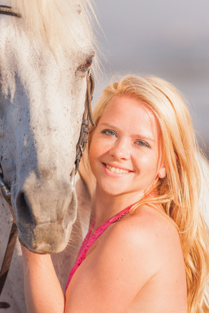 Beautiful young woman near a horse, she is happy to engage in a hobbyの写真素材