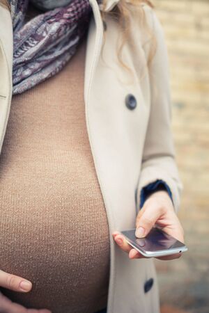 pregnant woman outdoor, calling to ambulance by mobile phoneの写真素材