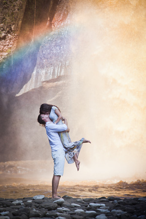 image of couple travels to balinese waterfall with beautiful rainbowの写真素材