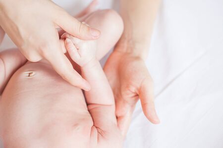 Mother makes nursing baby massage, apply oil on the hand, with white backgroundの写真素材