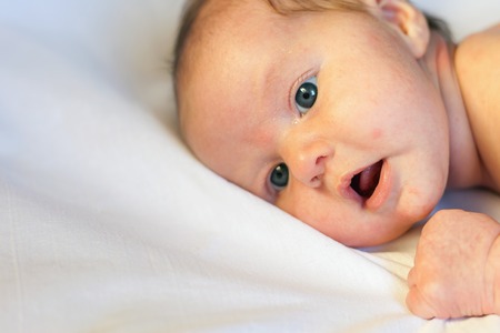 Newborn baby lying on a white background, the face has acneの写真素材