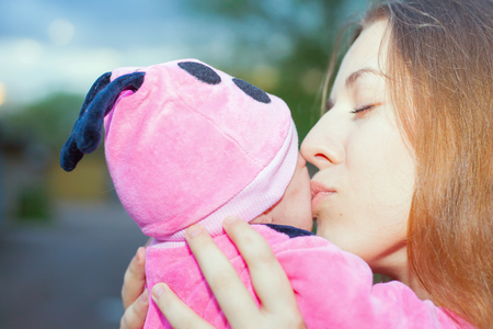 happy mother kissing a baby at outdoor, baby wearing a spring costumeの写真素材