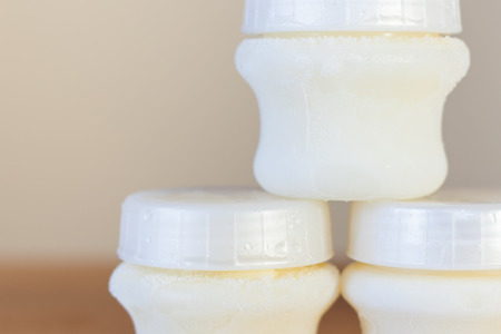 Baby bottle with milk, on the background of a lot of full bottles of breast milk. Mother's milk - the most healthy food for newbornの写真素材