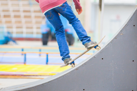 close-up image of teenager doing a trick by skateboard on a kicker in the skate park outdoors, focus at the foreground on a kickerの写真素材