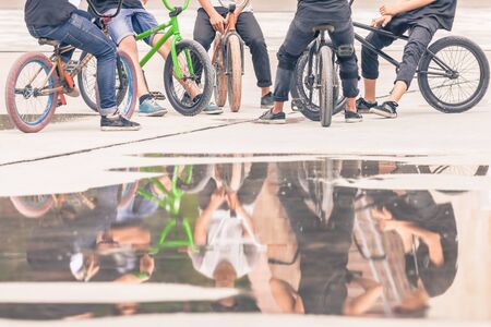 group of teenagers on a bikes at outdoor, freestyle park with reflection for copy spaceの写真素材