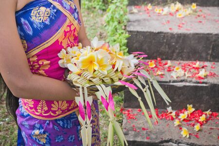 Traditional flower culture in Bali during the wedding ceremony or cremation. Young girl holding flowers in their hands for the offerings to the gods, or the newlywedsの写真素材