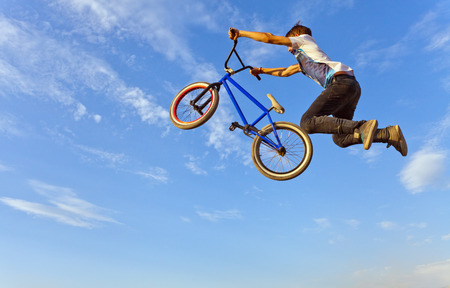Image of teenager on a bicycle in a jump on a background blue sky.の写真素材