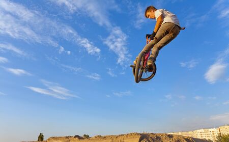 Image of teenager on a bicycle in a jump on a background blue sky.の写真素材