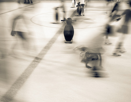 Black and white image of people who are ice skating in the ice rink, where the penguin is the...