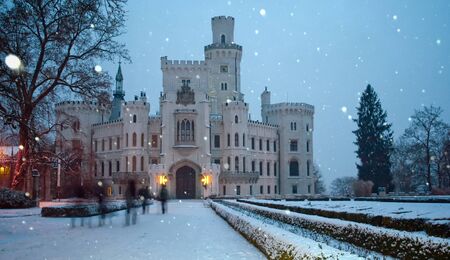 Winter landscape in the background of the castle Hluboka nad Vltavou. Walking people as inhabitants of the castle ghosts in the background of falling snow. Czech Republicのeditorial素材