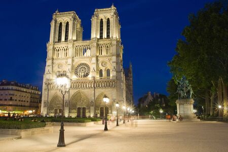 Night image of the famous cathedral of Notre-Dame in Paris against the backdrop of antique lighting lamps, France.の写真素材