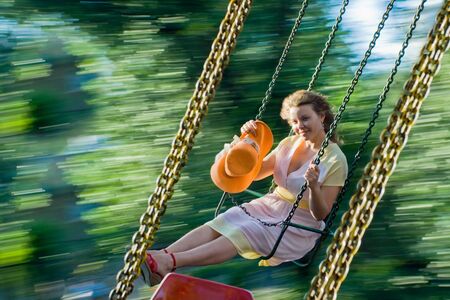 Beautiful young women swinging and smiling. Image of swing blurred motion and happy girl at summer.の写真素材
