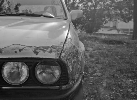 Black and white image of car standing outside near tree.