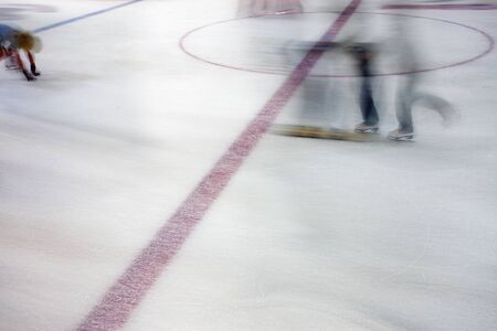 Image of people who are ice skating in the ice rink indoors.