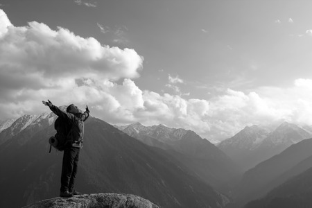 Climbing young adult at the top of summit with aerial view of the blue skyの写真素材