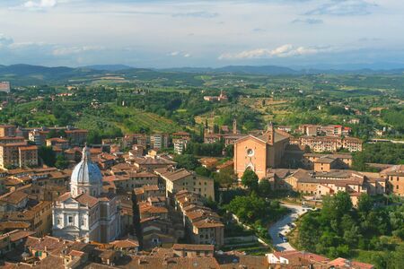 Panorama of Siena with numerous orange roofs against the horizon and sky with clouds.の写真素材